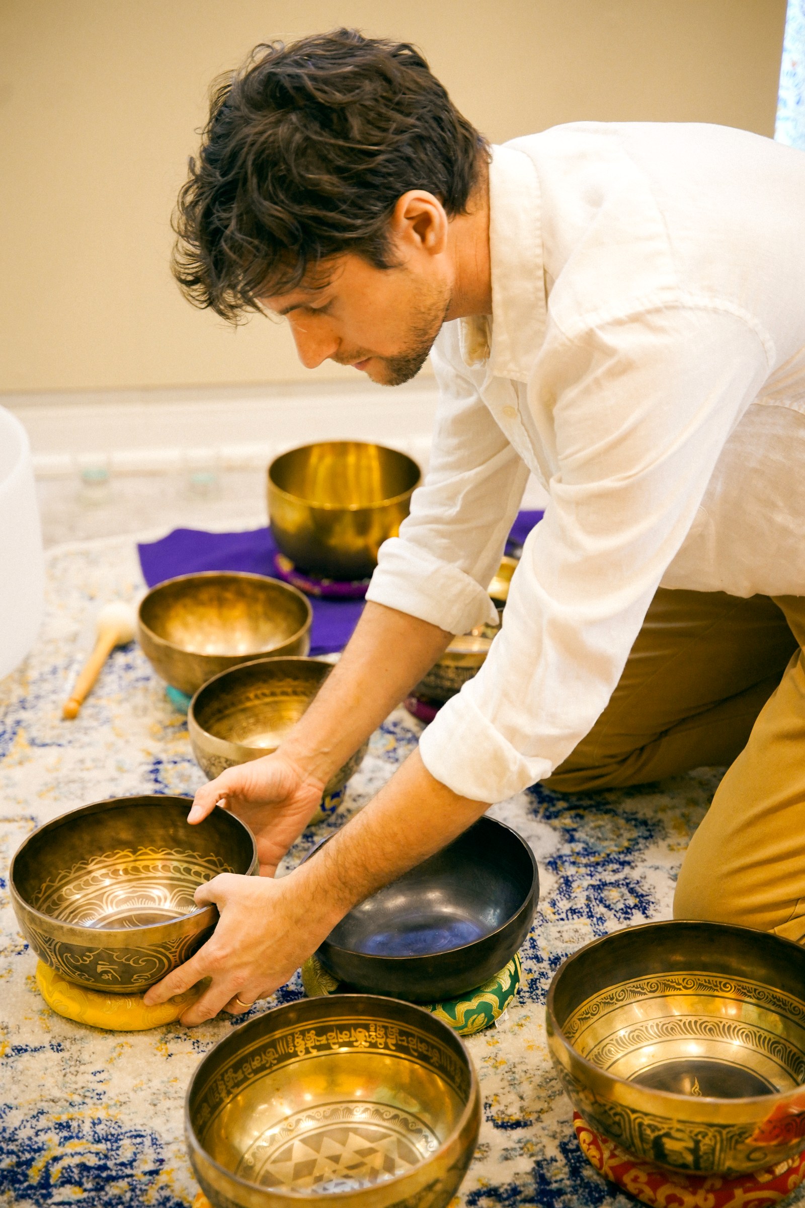 Dr. José Peralta arranging a row of Tibetan singing bowls before a session