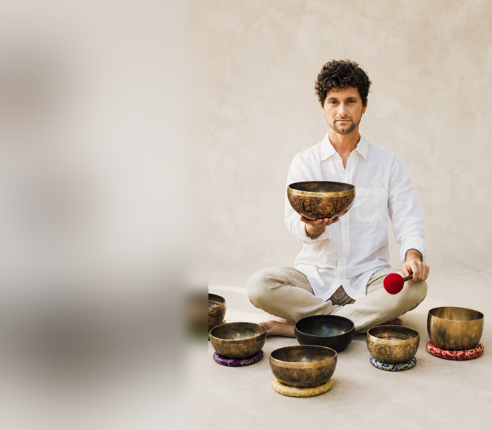 Dr. José Peralta seated with a Tibetan singing bowl, surrounded by his set of bowls