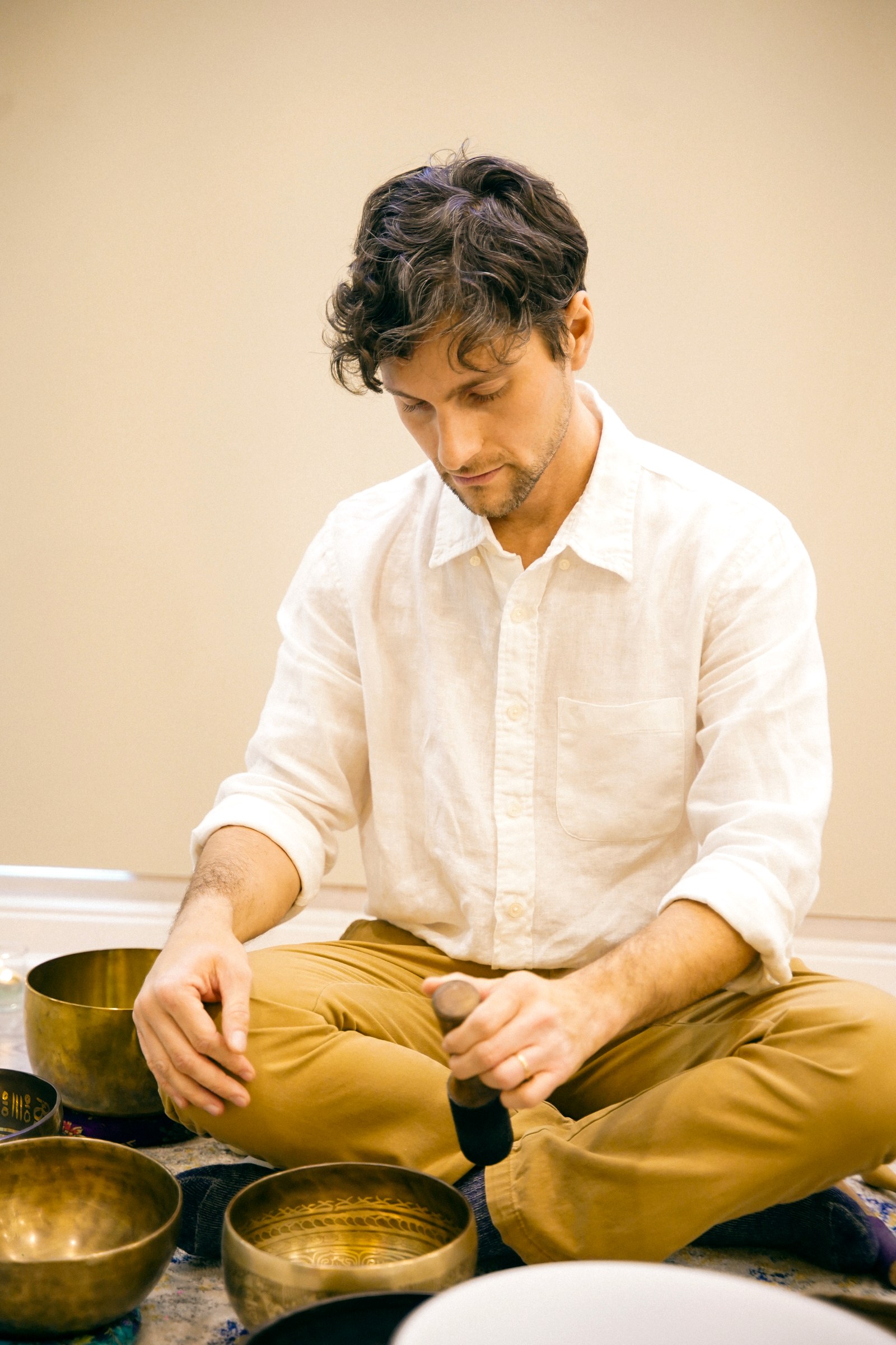 Dr. José Peralta seated with a Tibetan singing bowl, playing it with a mallet